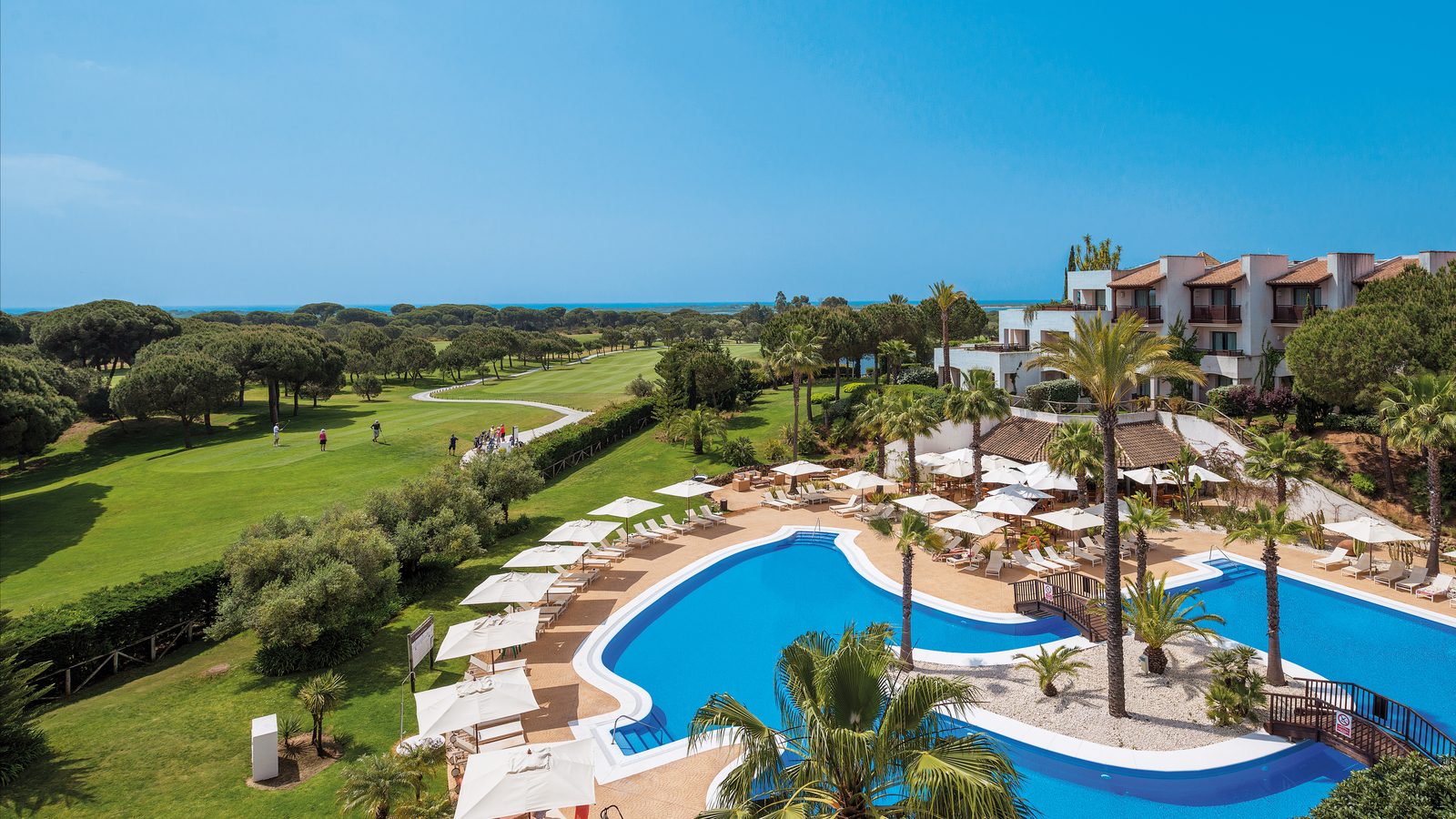 Precise Resort El Rompido pool and hotel, with the golf course beyond