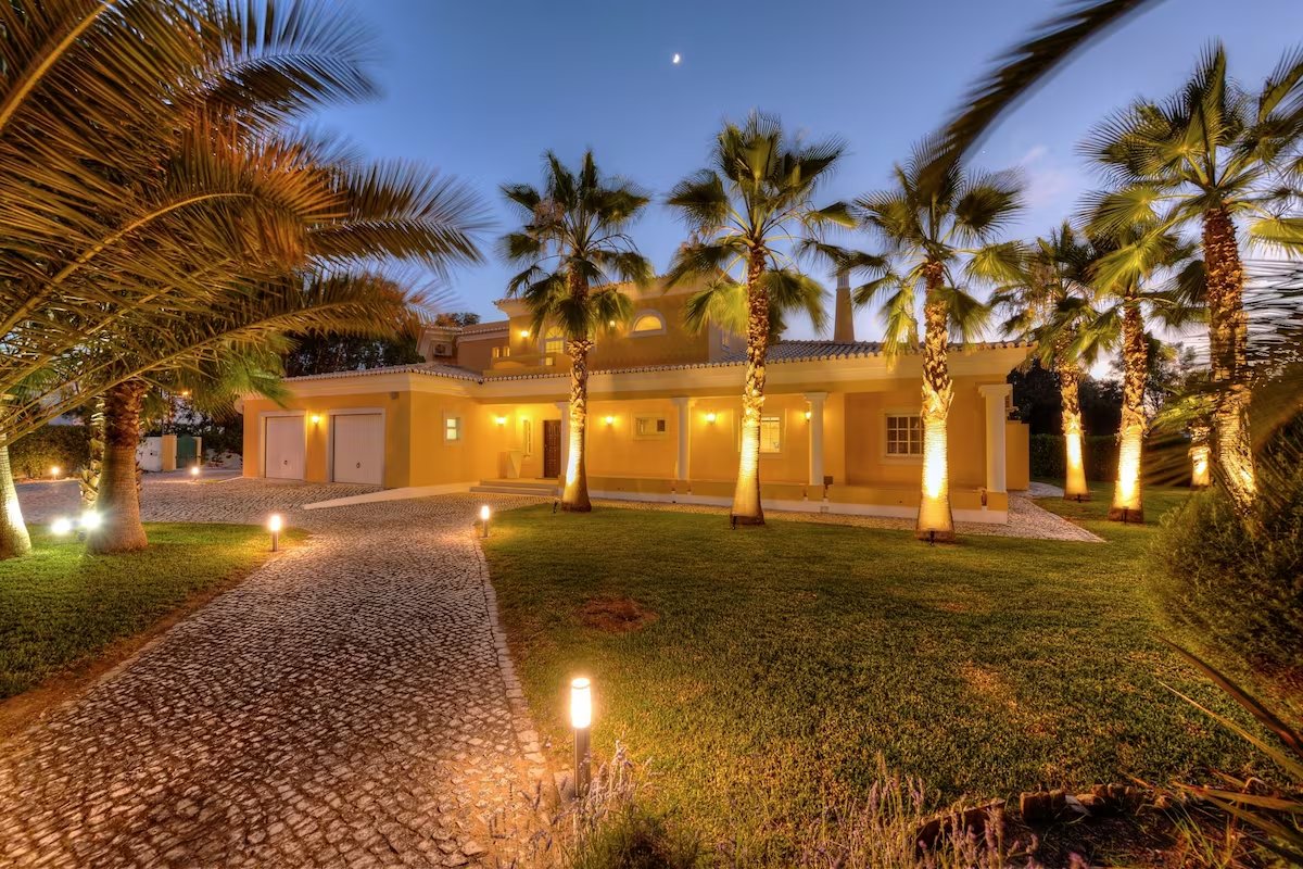 Algarve Distinción villa entrance at dusk, framed by palm trees
