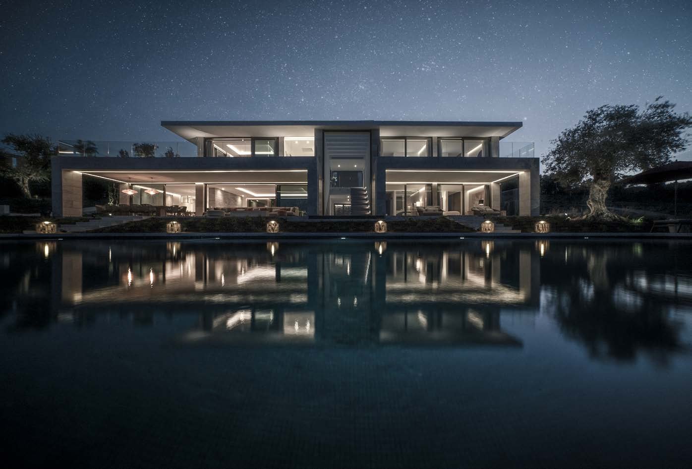 Villa La Escondida illuminated at night, with its reflecting pool