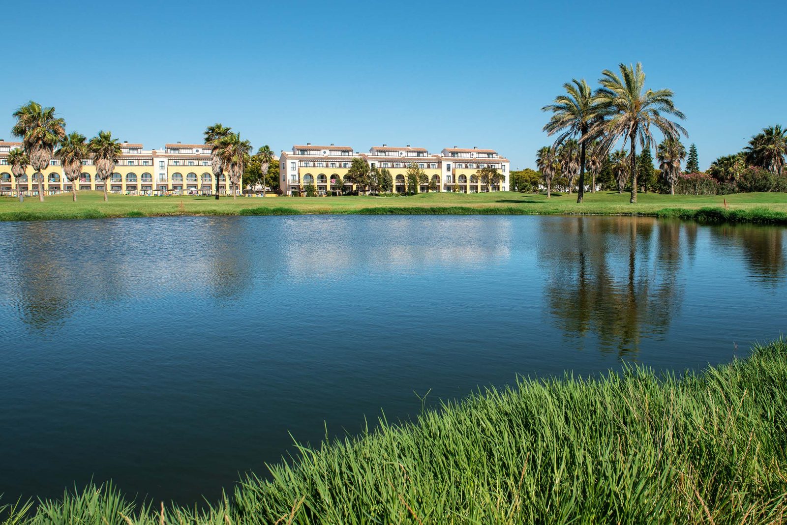 Costa Ballena resort buildings and palm trees reflected in the lake
